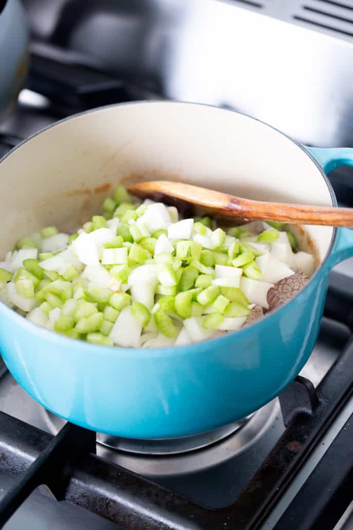 stockpot on stovetop filled with celery and onions