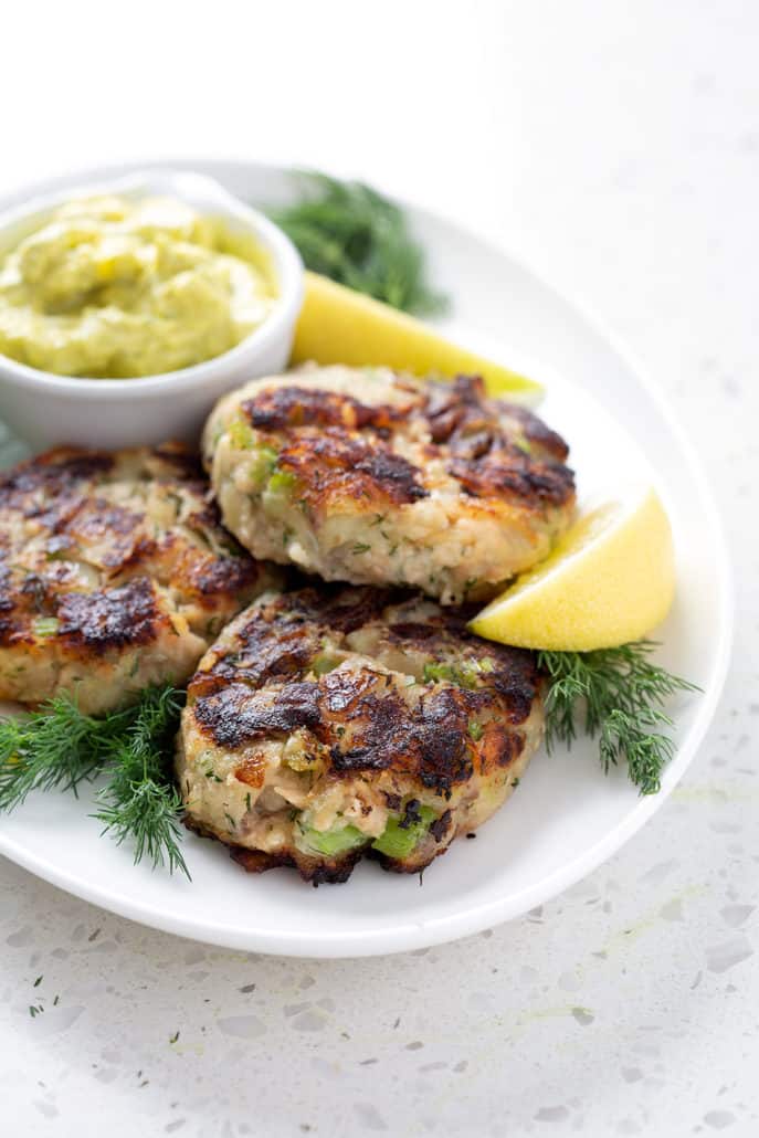 platter of aip salmon cakes surrounded by lemon slices, dill and dip