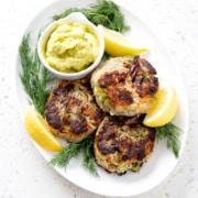 platter of aip salmon cakes surrounded by lemon slices, fresh dill and dip
