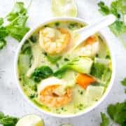 bowl of AIP Coconut Milk Curry Soup surrounded by cilantro and limes