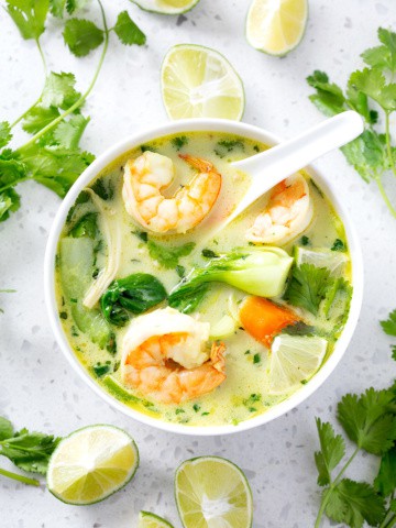 bowl of AIP Coconut Milk Curry Soup surrounded by cilantro and limes