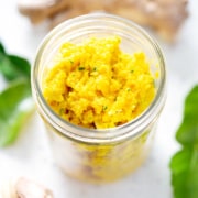 aip thai yellow curry paste in mason jar surrounded by ginger, lime leaves and galangal