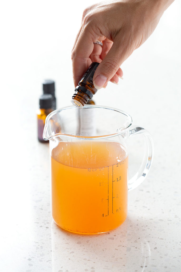 pouring essential oils in measuring cup on white background