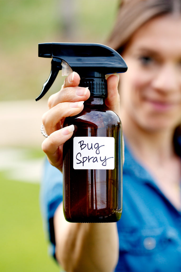woman holding amber glass spray bottle with words bug spray