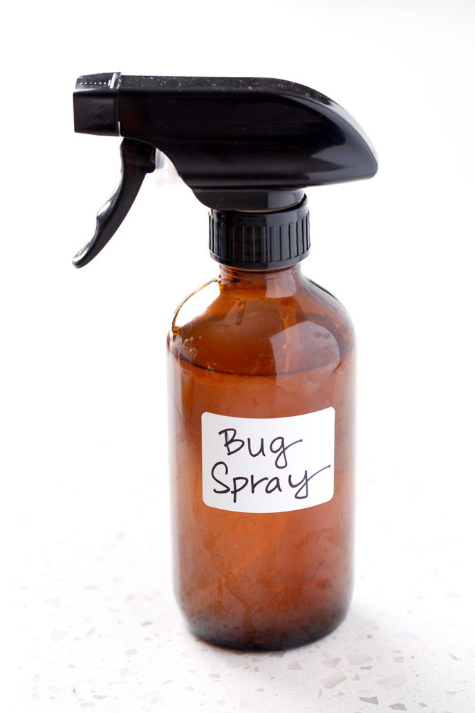 amber glass spray bottle with words bug spray on white background