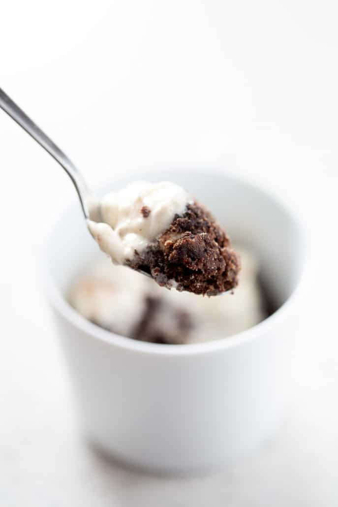 spoonful of AIP Chocolate Cake, vanilla frosting with blurred mug in background