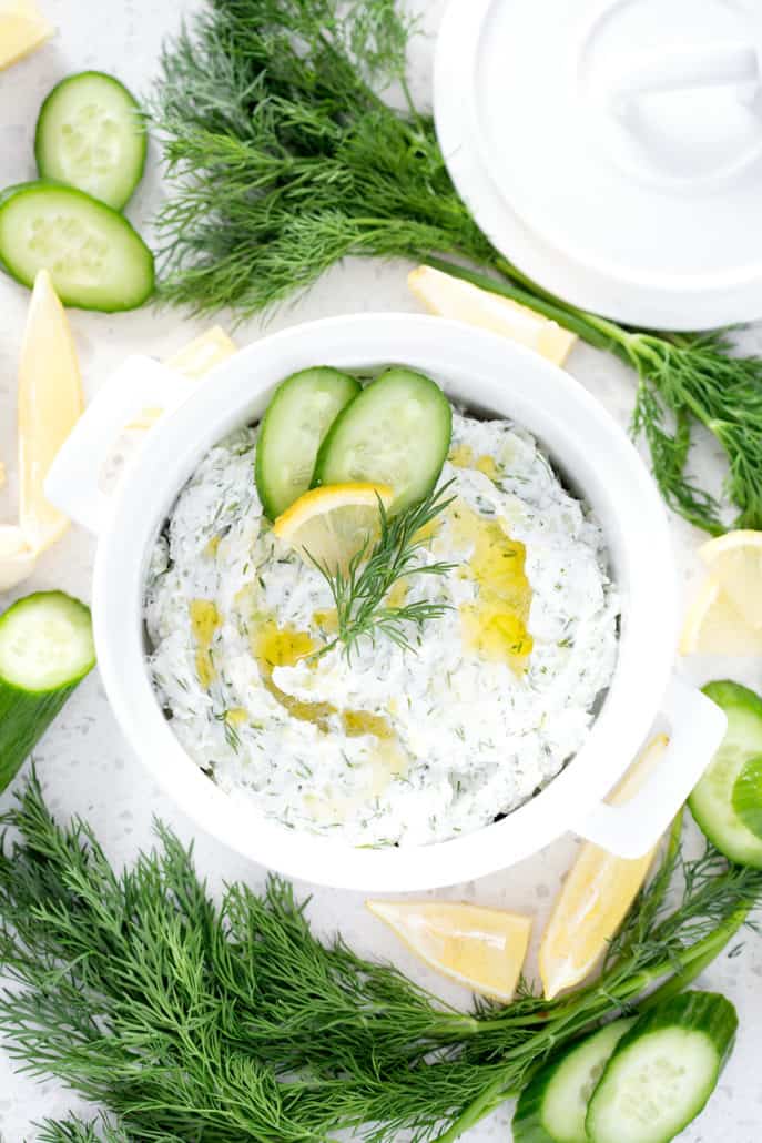 bowl of Dairy Free Tzatziki surrounded by cucumbers, dill and lemon