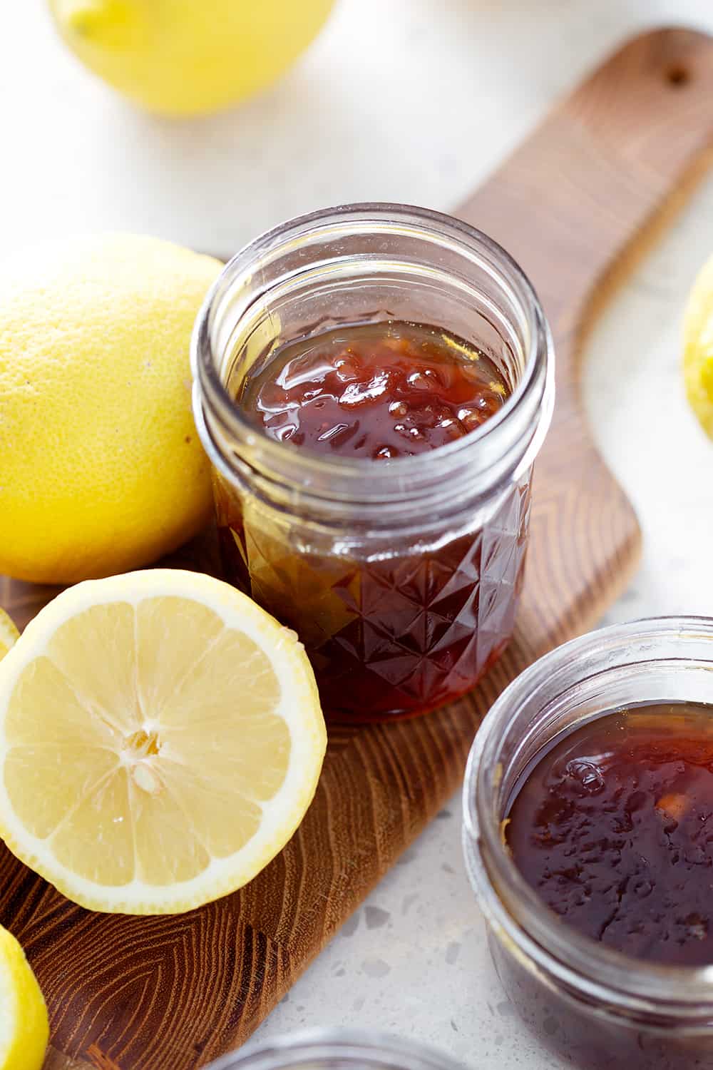 mason jars of Lemon Honey Marmalade on cutting board with lemons