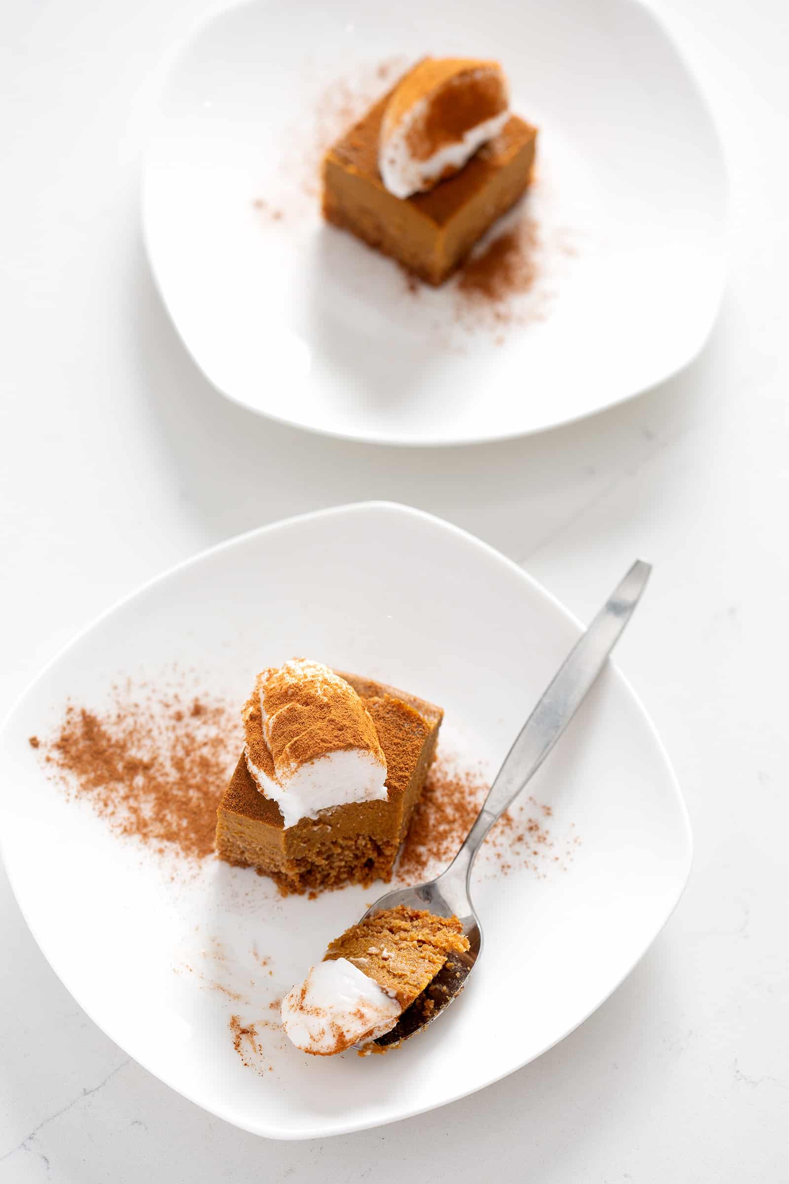 AIP Pumpkin Pie Bars on white plates with topping on what counter