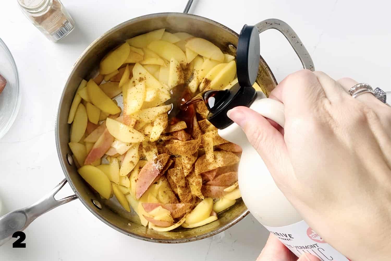 pouring maple syrup in cooking apples with cinnamon