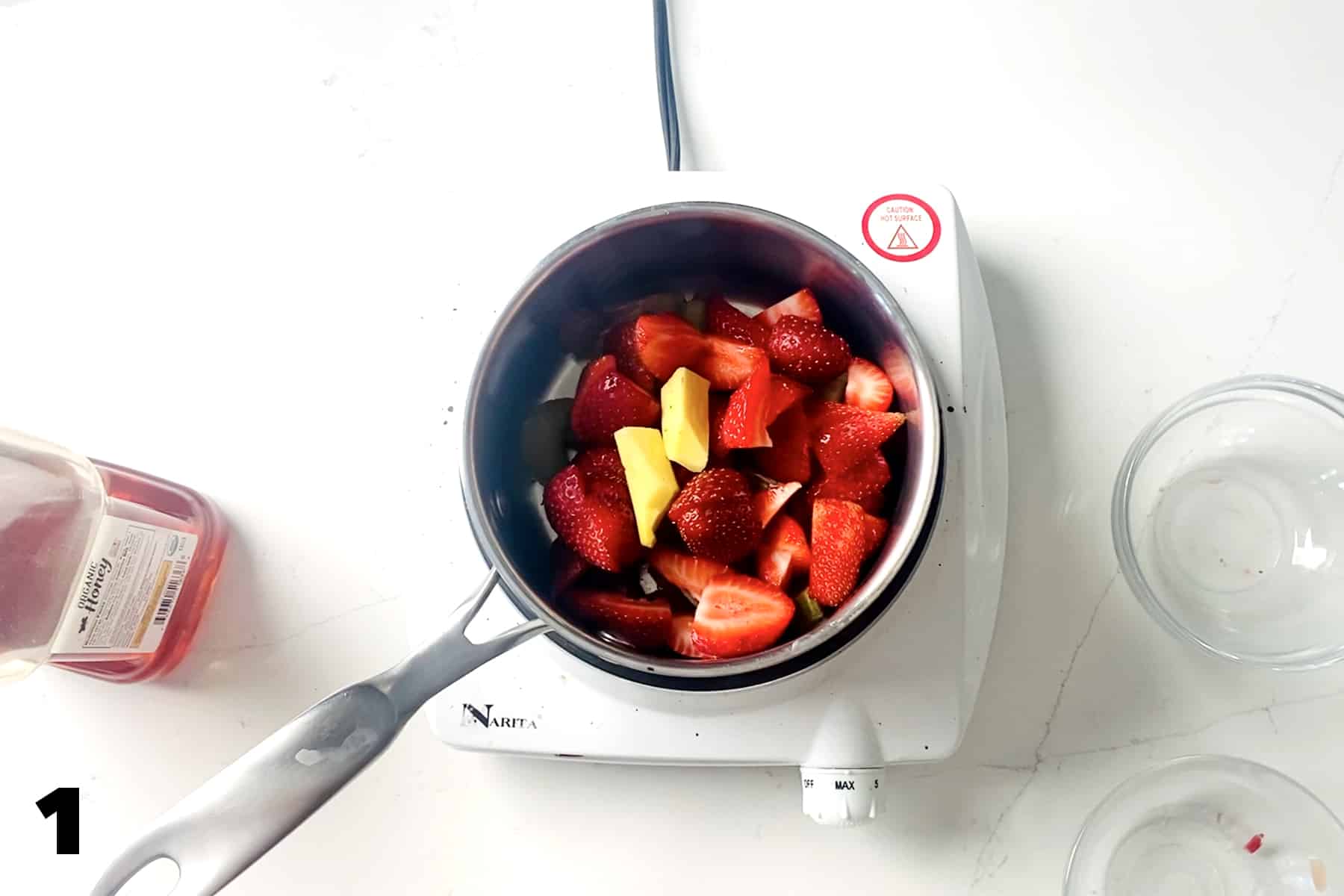 saucepan on cooktop with strawberries and ginger