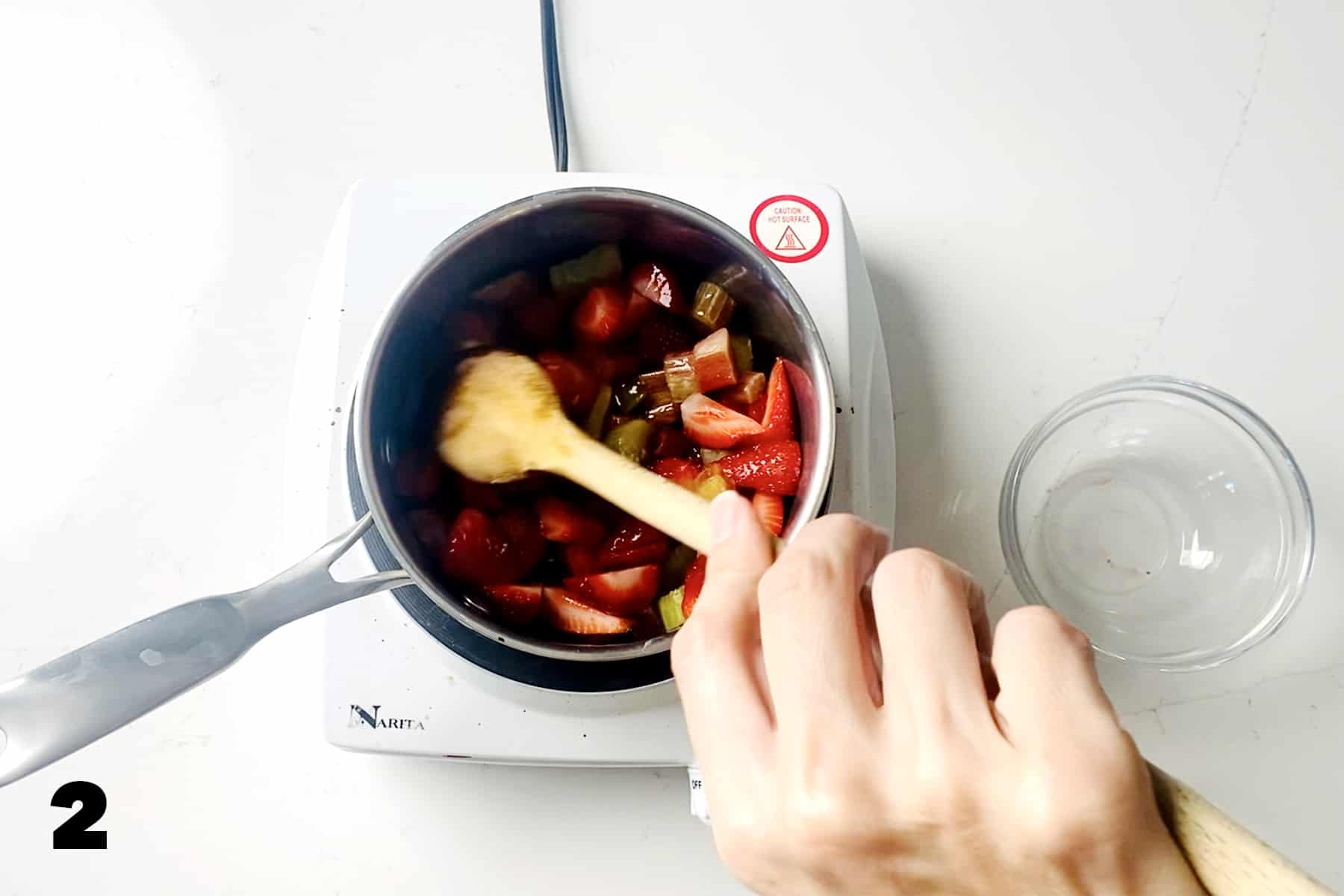 stirring strawberries and rhubarb in saucepan on cooktop