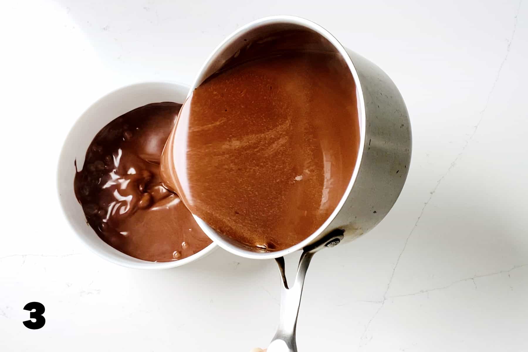 pouring chocolate mixture from saucepan to casserole dish on white counter