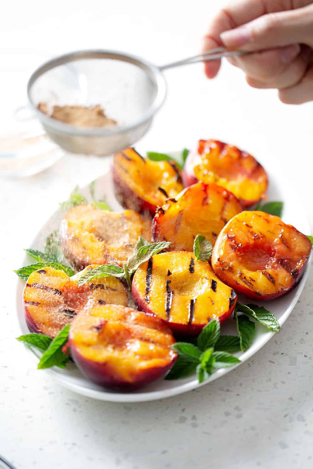 sprinkling sugar over grilled peaches