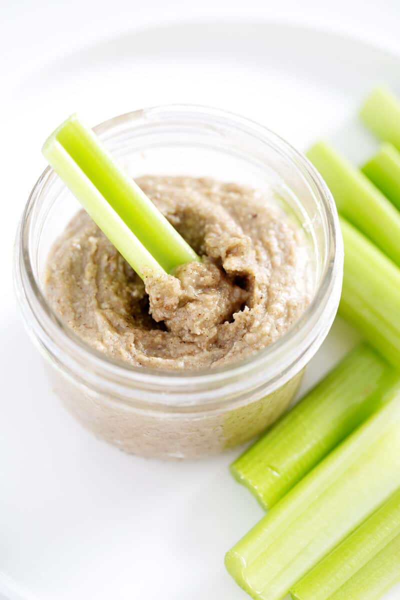 celery in mason jar of tigernut butter on plate with more celery
