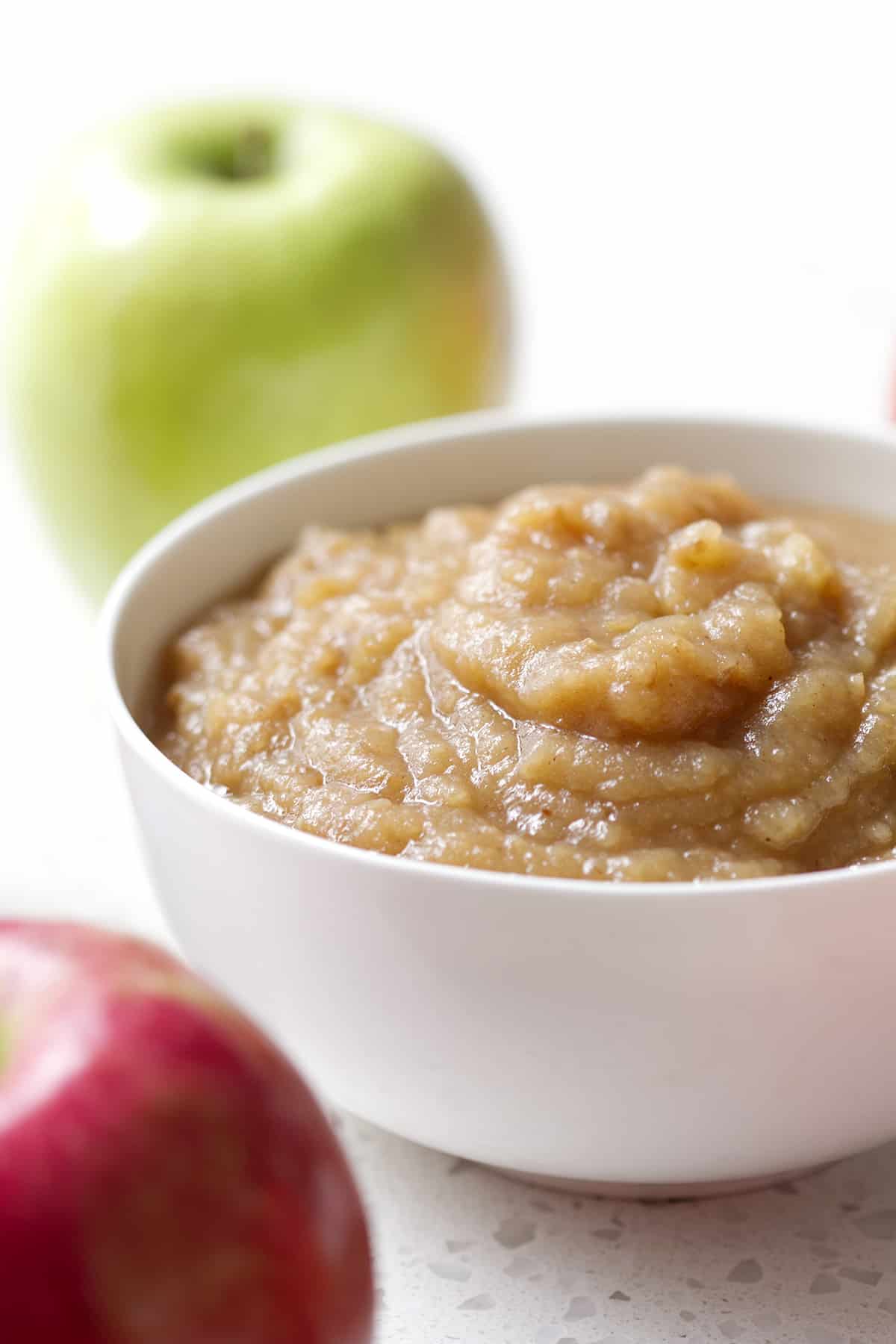 bowl of unsweetened applesauce with apples in background