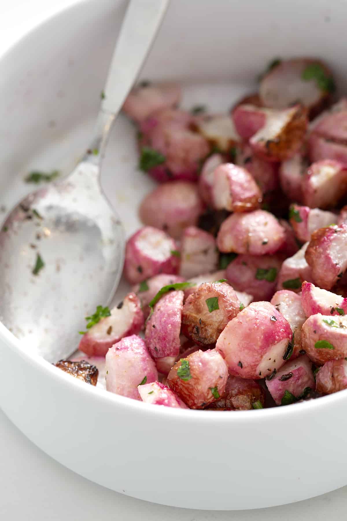 close up of bowl of air fryer radishes with spoon