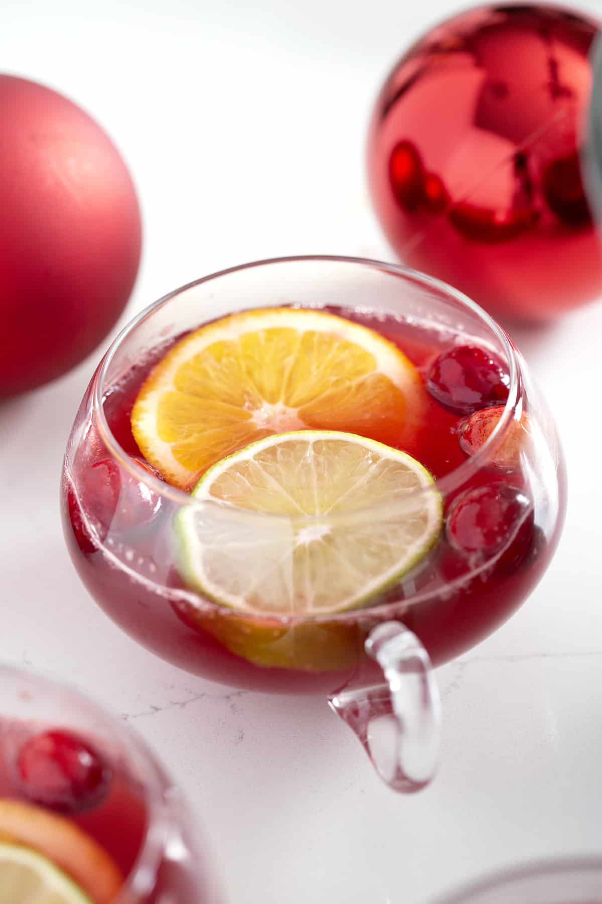 punch glass filled with red non alcoholic christmas punch with citrus slices