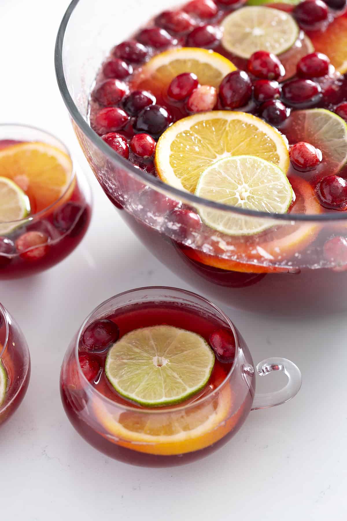 punch bowl and glasses filled with non alcoholic Christmas Punch, citrus, cranberries