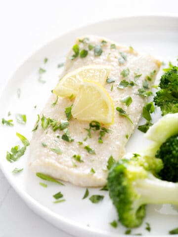 halibut fillet with parsley and lemon slices on plate