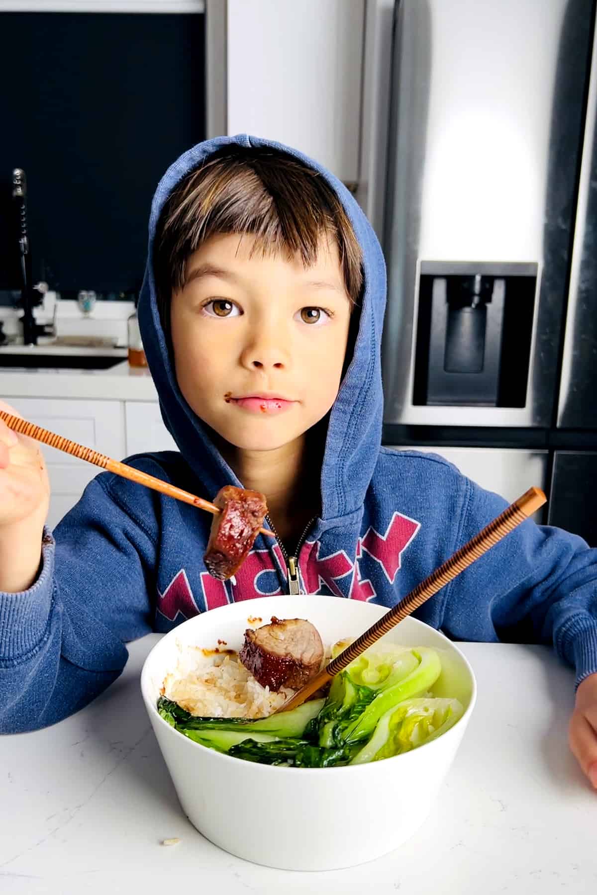child eating Chinese bbq pork tenderloin with chopsticks
