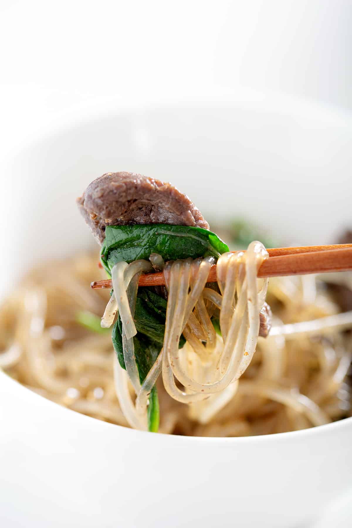 chopsticks with glass noodles, spinach and beef