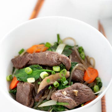 bowls of sweet potato glass noodles with vegetables and chopsticks