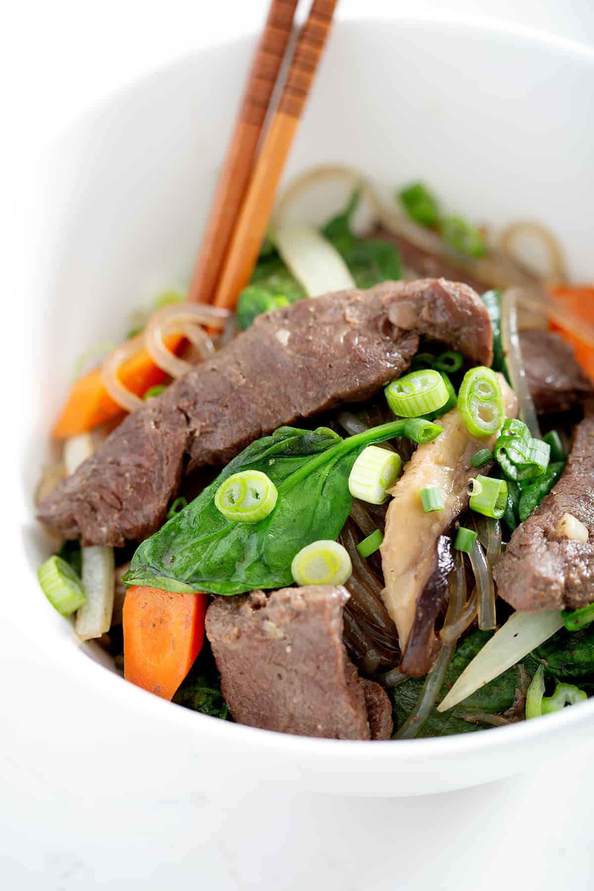 bowl of sweet potato glass noodles stir fry with beef and vegetables