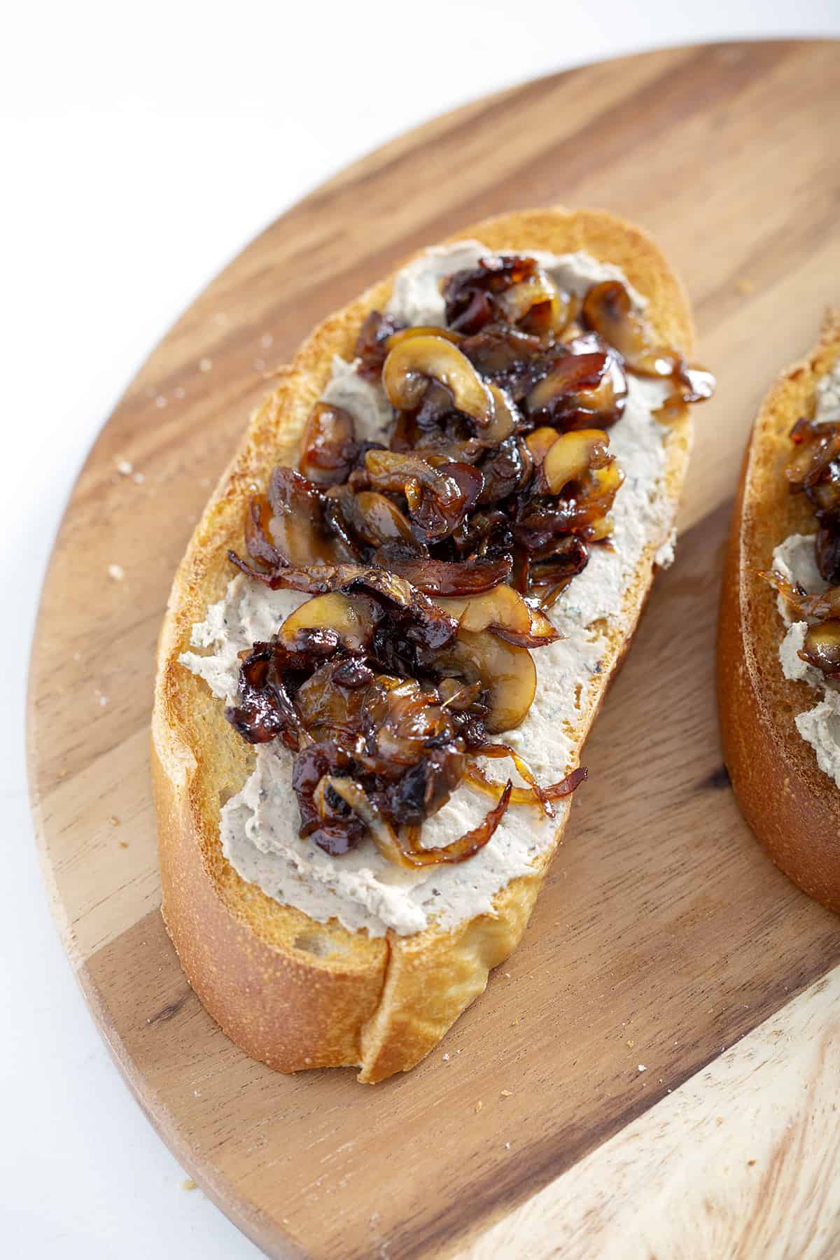 toast with pate and caramelized onions and mushrooms on wooden cutting board