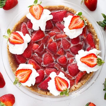 no bake strawberry pie with whipped cream surrounded by strawberries