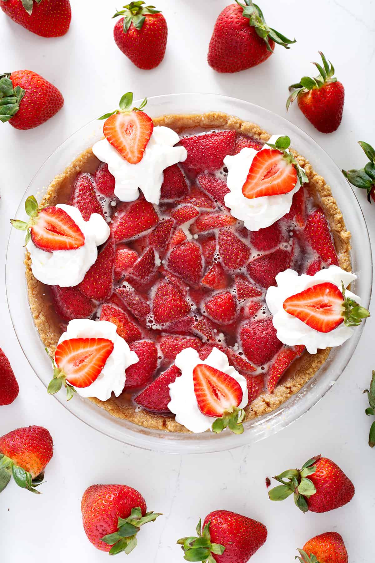 strawberry pie with graham cracker crust topped with fresh whipped cream