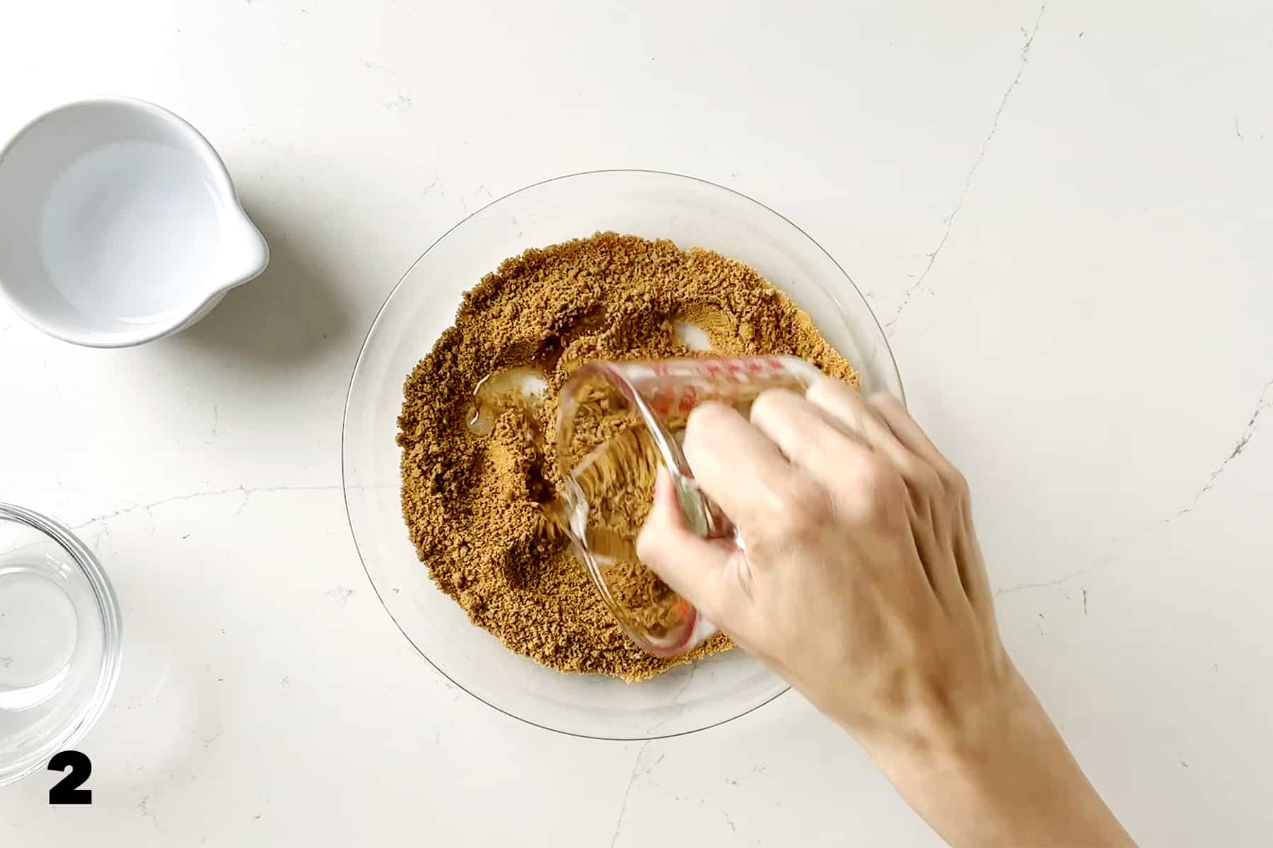 pouring water into graham cracker crumbs in pie plate