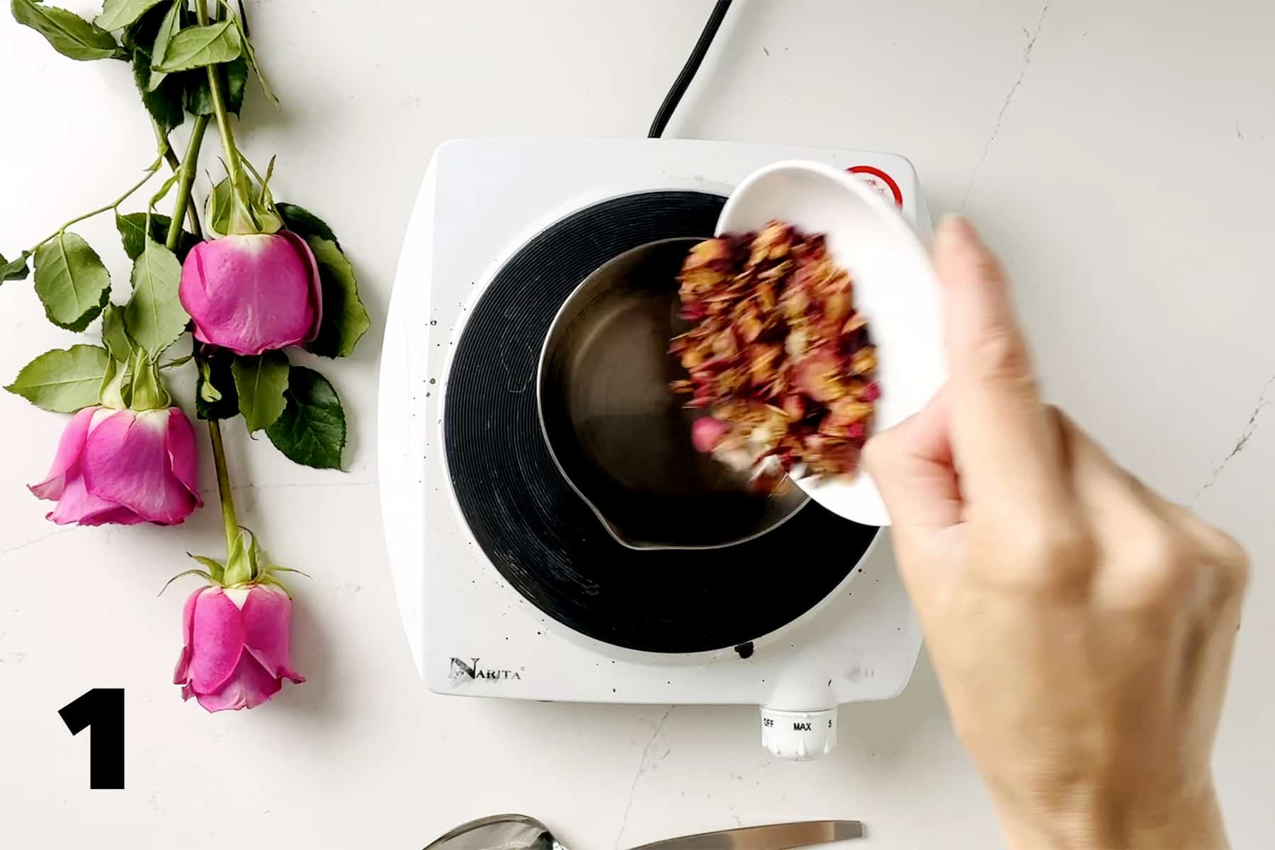 pouring dried rose peals into small pan surrounded by pink roses