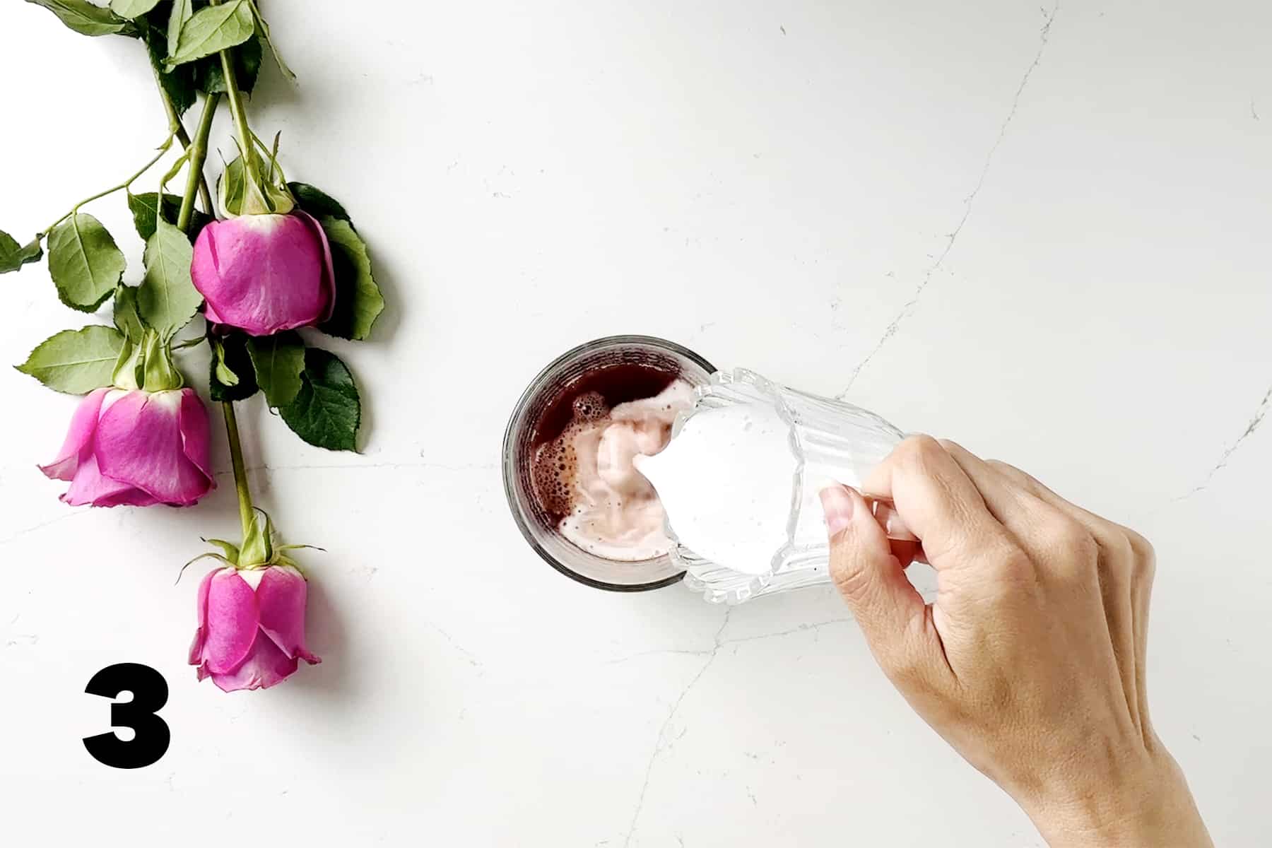 pouring coconut milk into mug surrounded by pink roses
