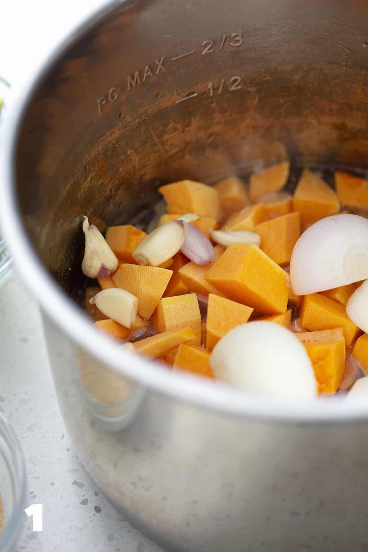 instant pot filled with onions, garlic and chunks of butternut swuash