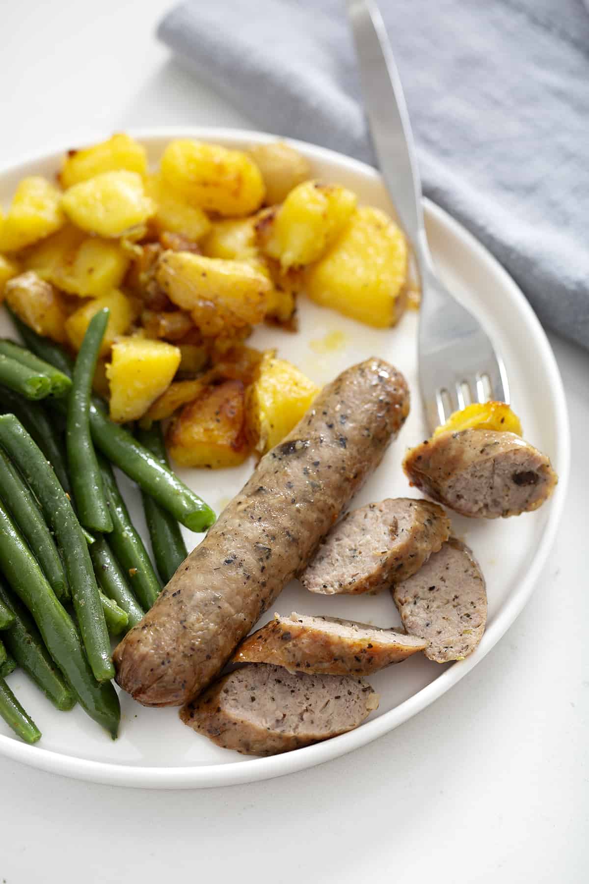 potatoes, air fryer chicken sausage and green beans on plate with fork