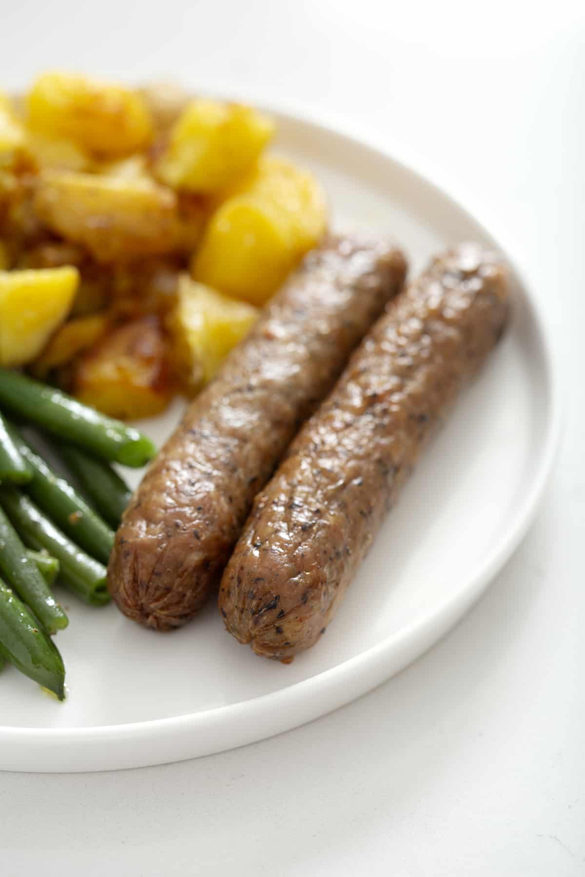 sir fryer chicken sausage on plate with potatoes and green beans