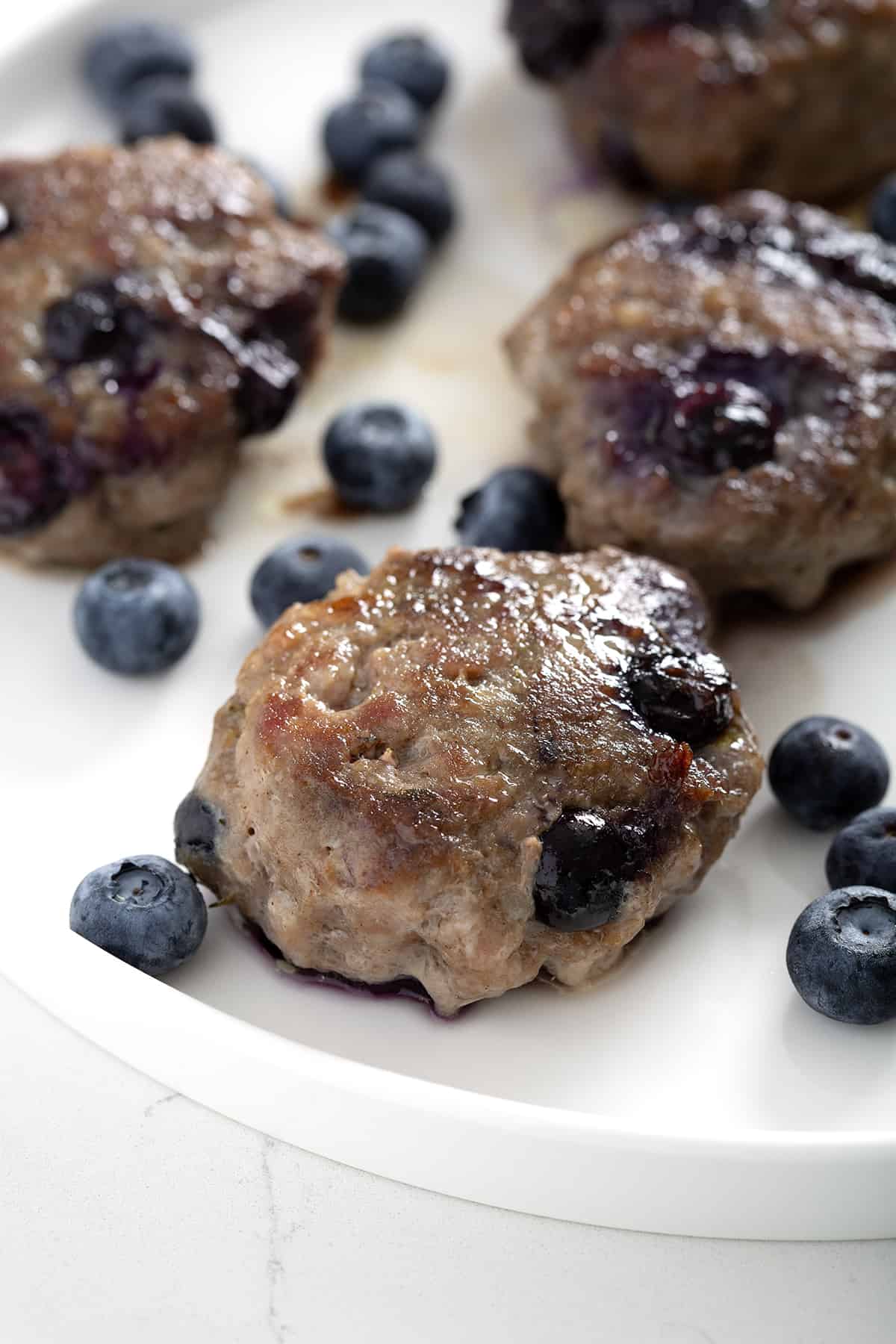 blueberry sausage on a white plate with fresh blueberries