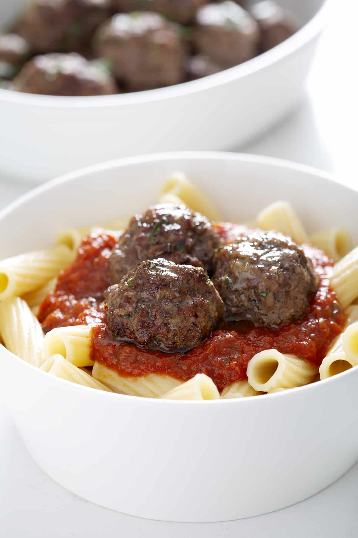 air fryer bison meatballs in white bowl with marinara sauce and pasta 