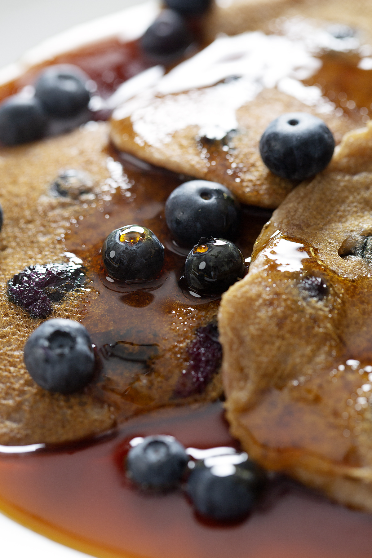 stack of blueberry pancakes with maple syrup and blueberries