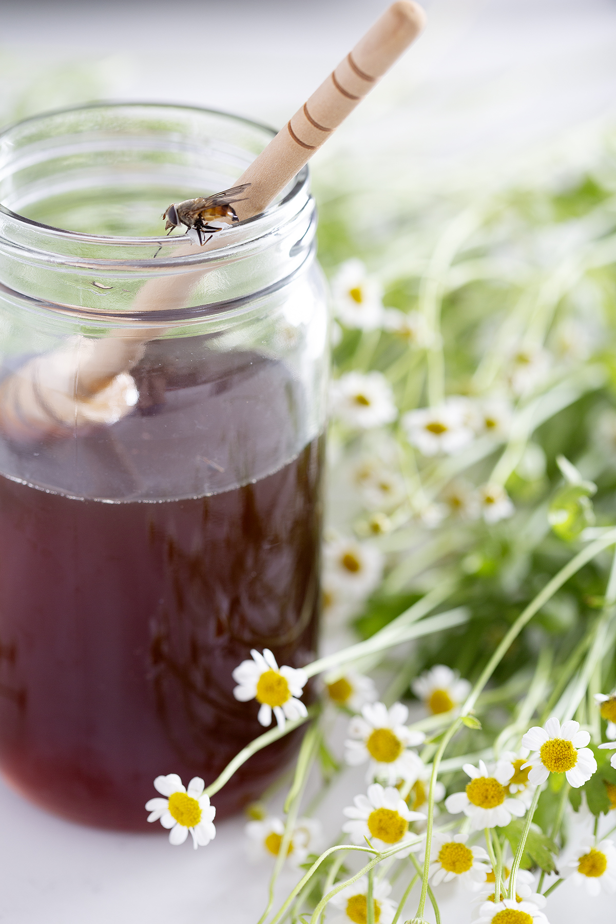 jar of honey with dipper, bee and flowers