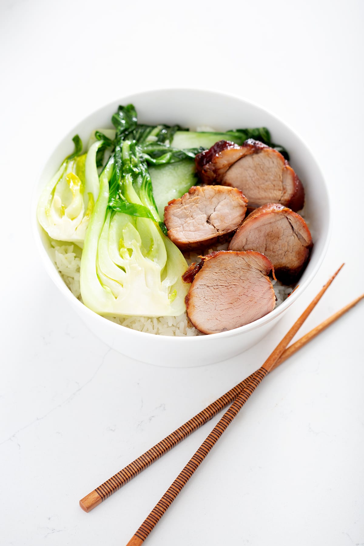 bowl of char siu pork with shanghai bok choy with chopsticks