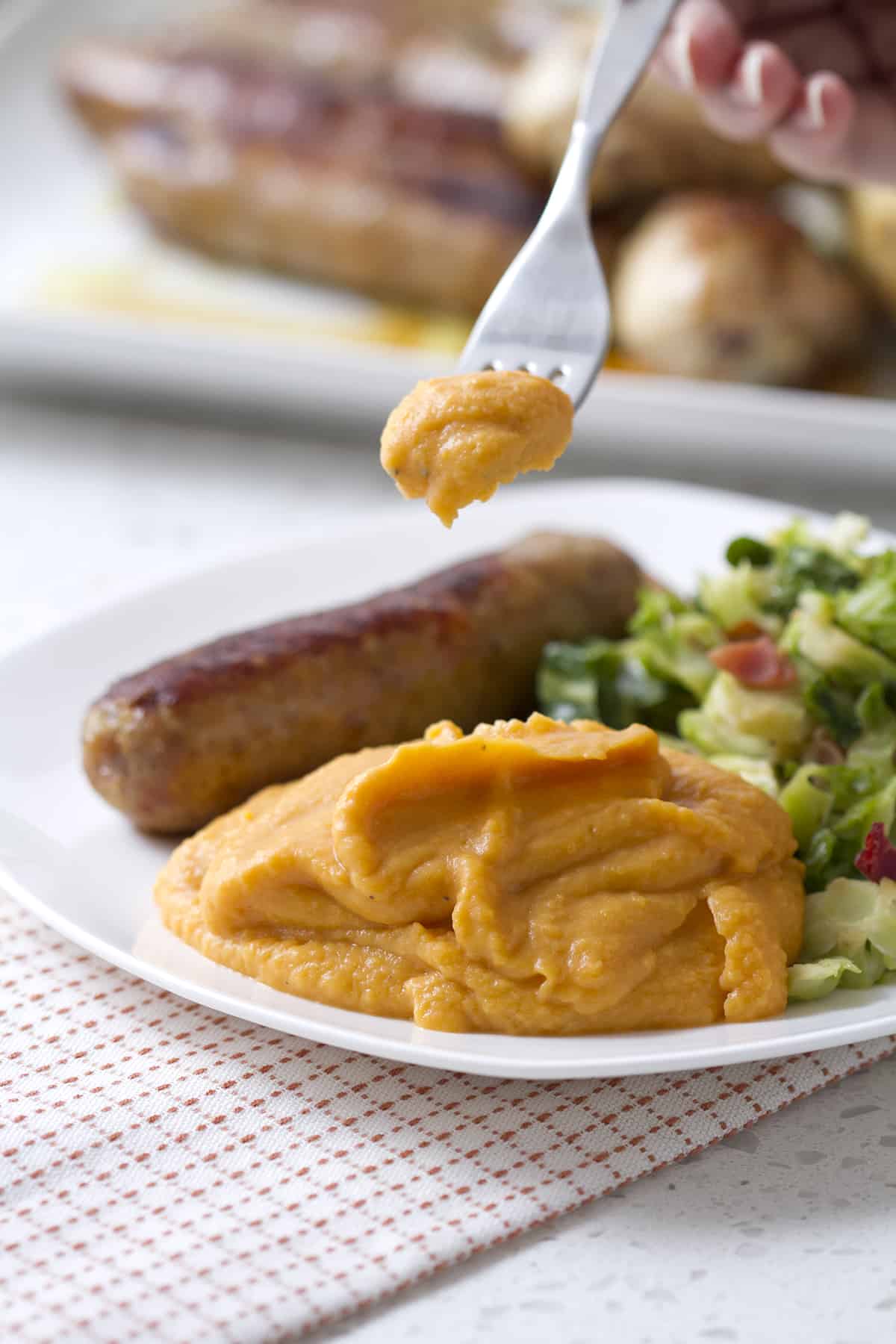 forkful on mashed sweet potatoes being held over plate