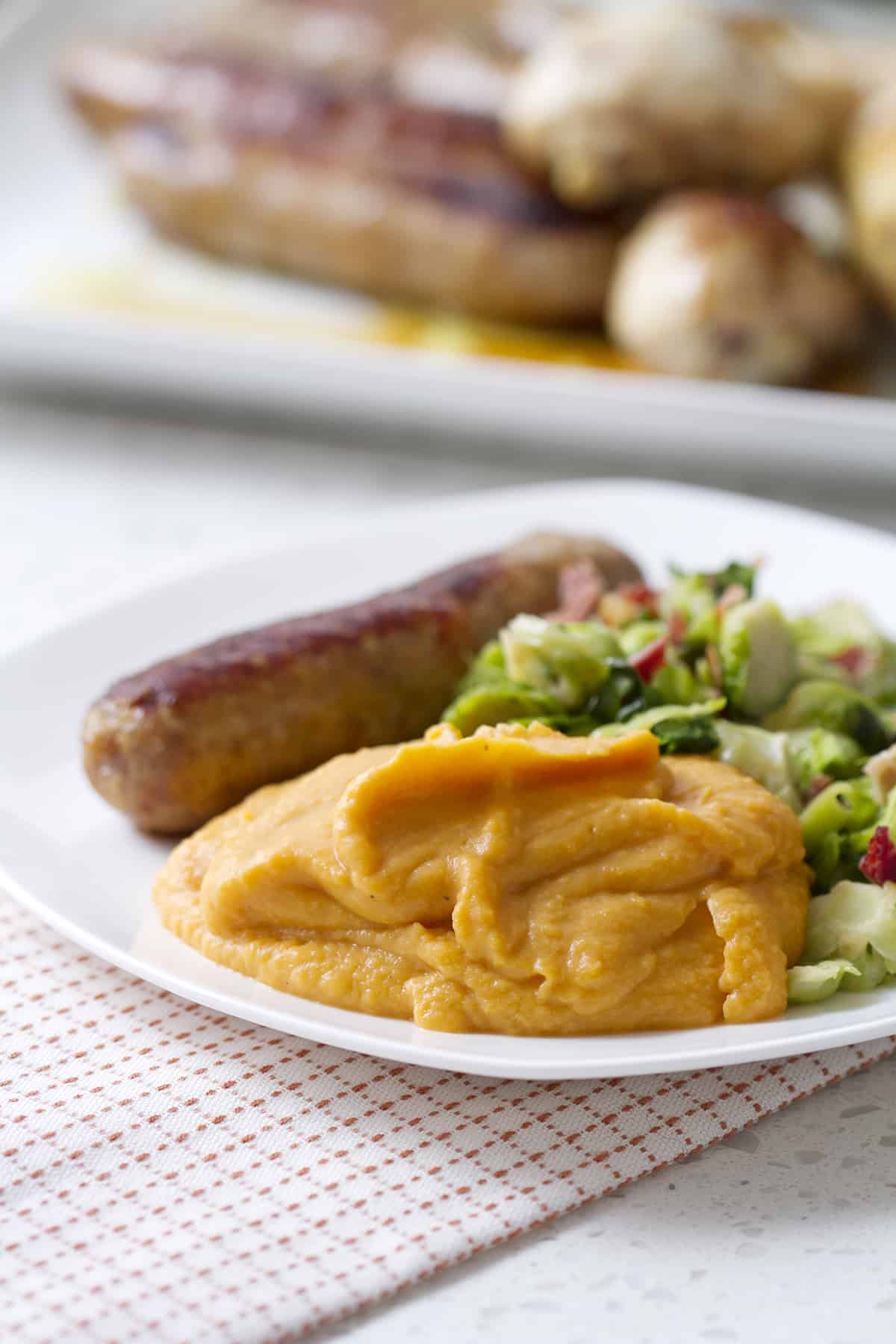 plateful of mashed sweet potatoes, sausage and brussel sprouts