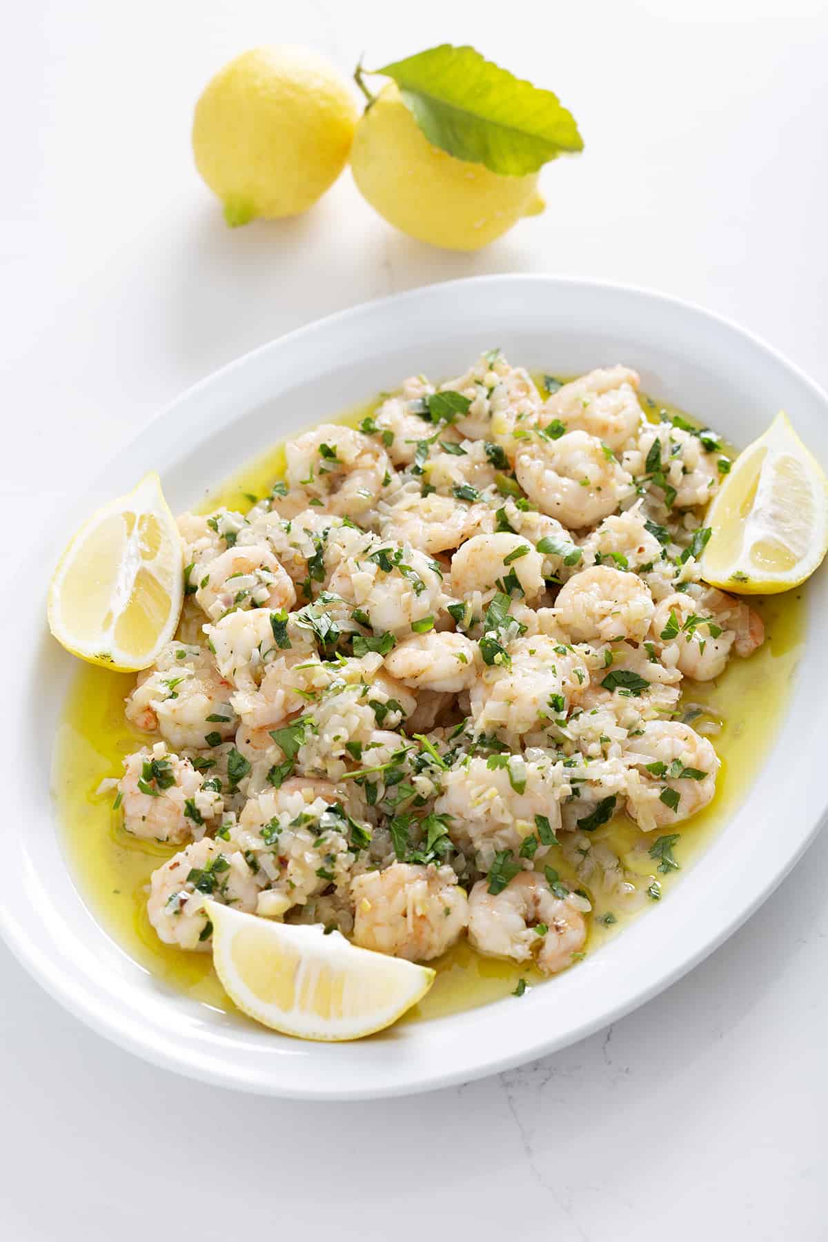 platter of dairy free shrimp scampi with lemons on white counter