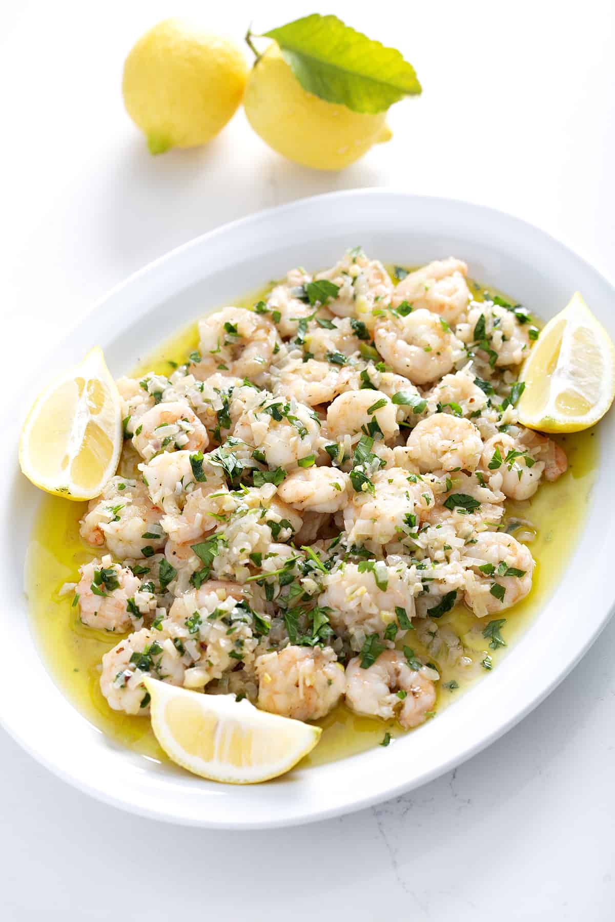 platter of dairy free shrimp scampi with lemons on white counter