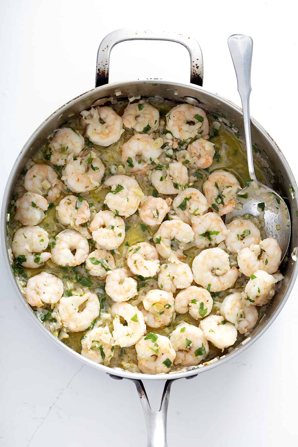 pan of dairy free shrimp scampi with spoon on white counter
