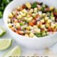 bowl of pineapple pico de gallo surrounded by cilantro, limes, tortilla chips