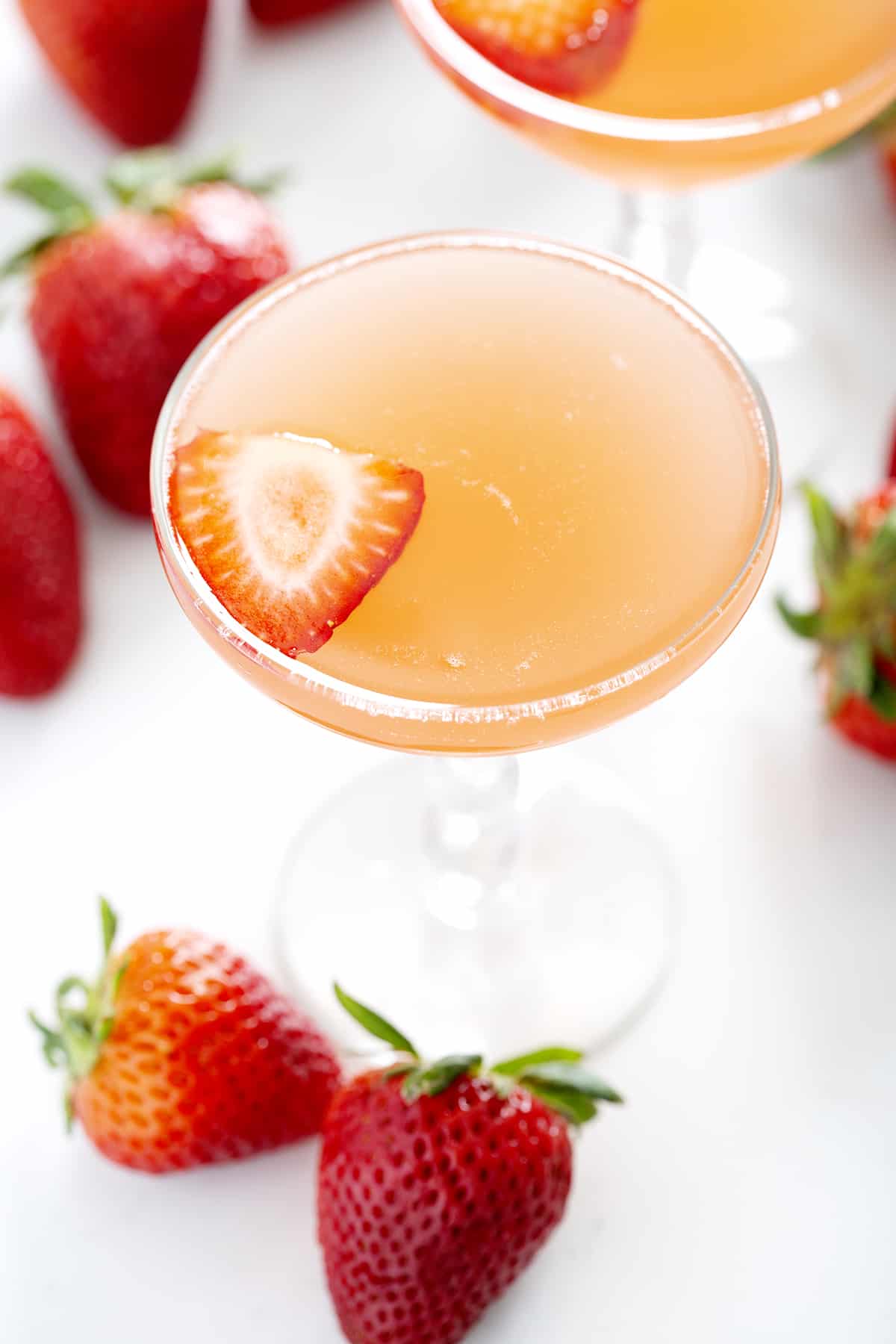 champagne coupe filled with Strawberry Rhubarb French 75 garnished with strawberry slice