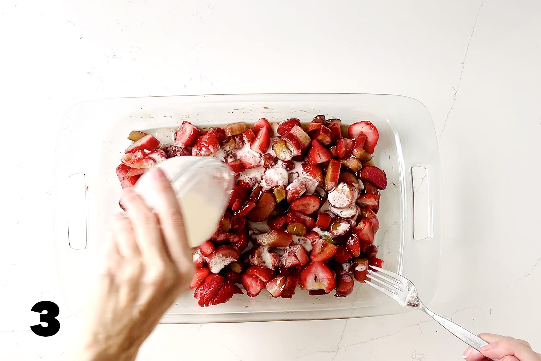 pouring slurry over strawberry rhubarb mixture into glass pan